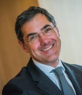 Charlie MacQuaker smiling at the camera, with the image angled diagonally.