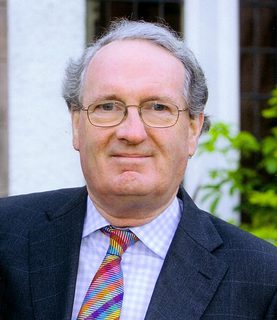 Donald MacDonald, wearing a suit with a colourful tie, looks directly into the camera.