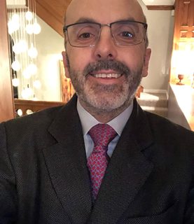 Close-up of Mark Urquhart wearing a suit, smiling at the camera.
