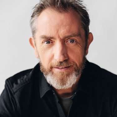 David Brophy smiles at the camera against a white background.