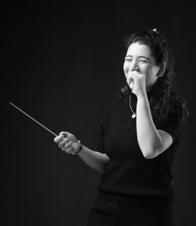 Black and white image of Nil Venditti laughing with a baton in her hand.