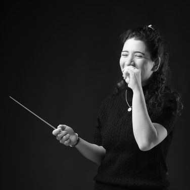 Black and white image of Nil Venditti laughing with a baton in her hand.