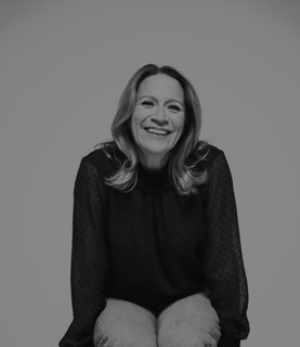 Carolyn Sampson sits on a bar stool, laughing.