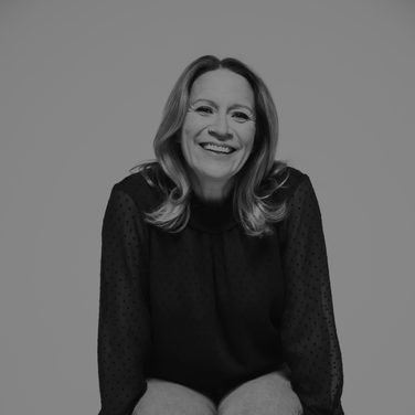 Carolyn Sampson sits on a bar stool, laughing.