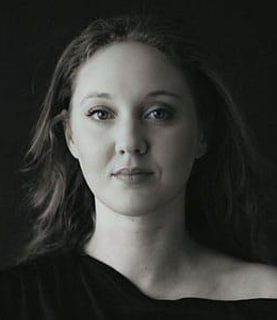 Bethany looks to the camera. She wears a black top.