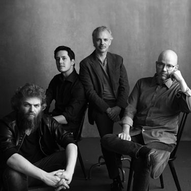 Monochrome image of Brooklyn Rider string quartet against a grey background.