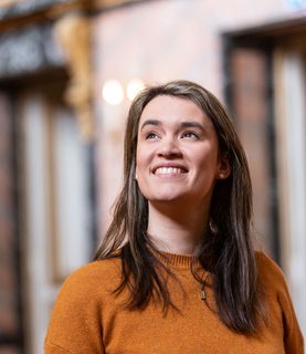 Mezzo-soprano Helen Charlston smiles in sunlight, gazing towards the top left corner of the image.