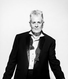 Horse wears a black suit and bowtie untied.