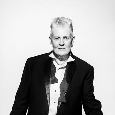 Horse wears a black suit and bowtie untied.