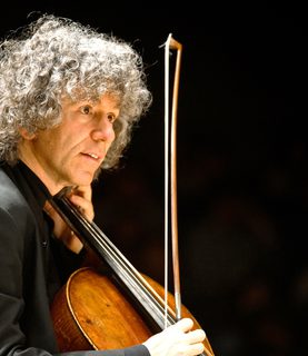 Cellist Steven Isserlis, seen from the side, plays the cello while looking towards the right of the image.