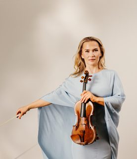Mari Samuelsen holds her violin, wearing a light blue gown.