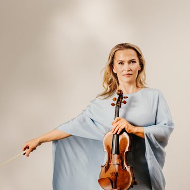 Mari Samuelsen holds her violin, wearing a light blue gown.