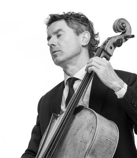Donald plays the cello. He wears a black suit and tie.