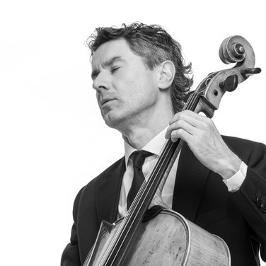 Donald plays the cello. He wears a black suit and tie.