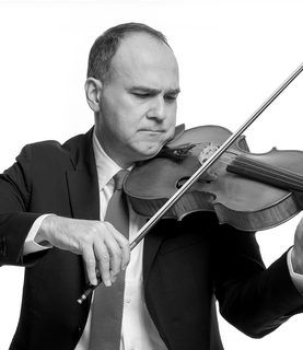 Max plays the viola. He wears a dark suits and white shirt.