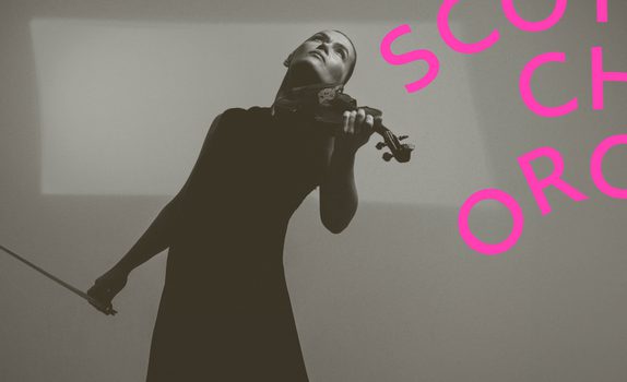 Mari Samuelson leans back and plays the vilin she wears a long black dress.