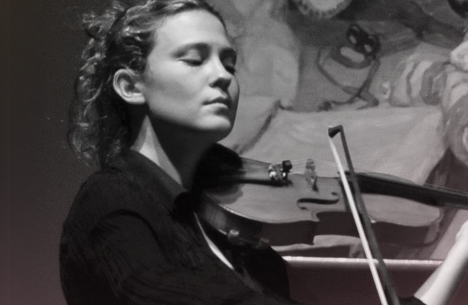 Lorenza Borrani plays the violin with an renaissance style painitng behind her.