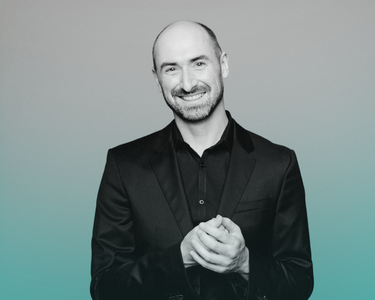 Peter Whelan wears a black shirt and smiles.