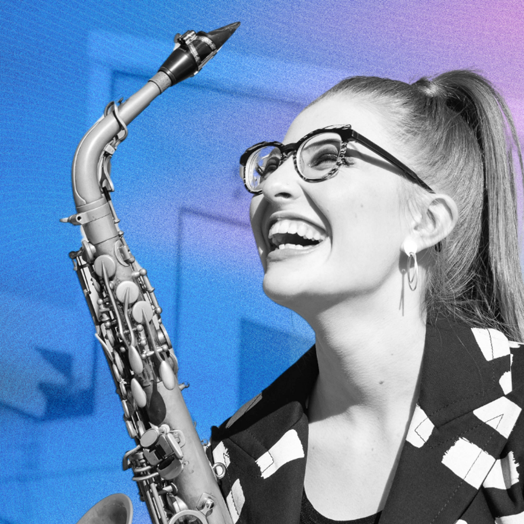 Jess Gillam smiles up holding her saxophone.