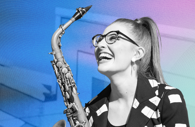 Jess Gillam smiles up holding her saxophone.