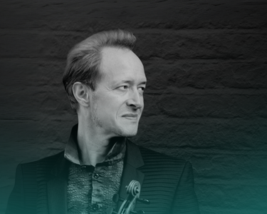 Andrew Marwood holds a violin and looks to his left.