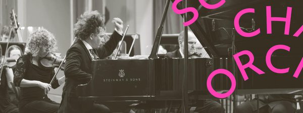Maxim passionately plays the piano while the orchestra play behind