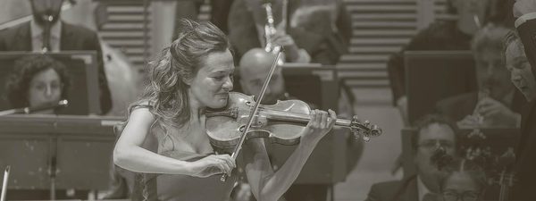 Benedetti smiles as she plays the violin. She weard a sleeveless light dress.