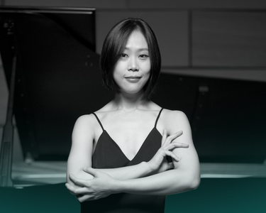 Yeol Eum Son stands in front of a piano with her arms crossed