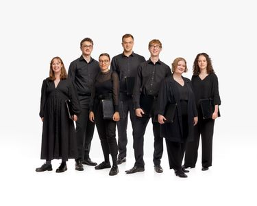 the seven SCO Young Singers' wear concert blacks and stand smiling with white backdrop