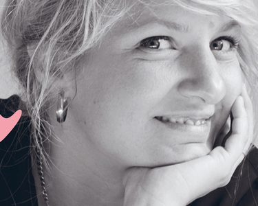 Composer Andrea Tarrodi leaning forward with one arm resting on a surface and her face resting on the palm of her other hand.