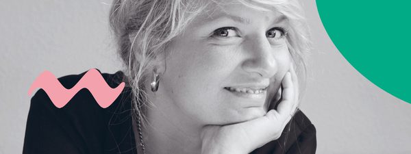 Composer Andrea Tarrodi leaning forward with one arm resting on a surface and her face resting on the palm of her other hand.