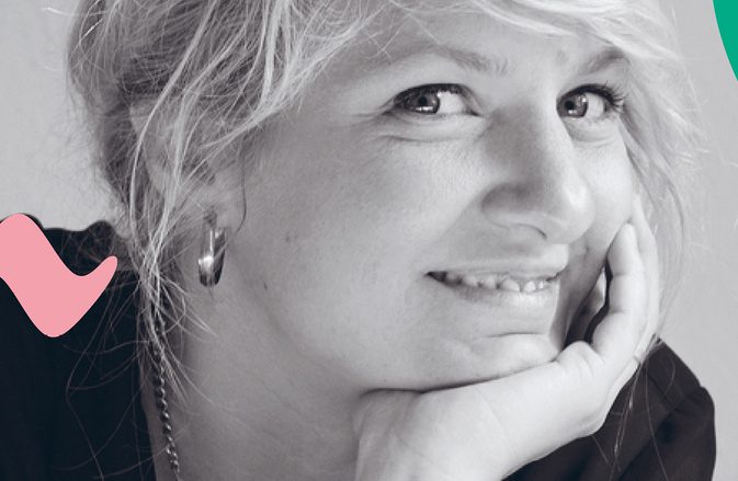 Composer Andrea Tarrodi leaning forward with one arm resting on a surface and her face resting on the palm of her other hand.