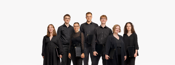 the seven SCO Young Singers' wear concert blacks and stand smiling with white backdrop