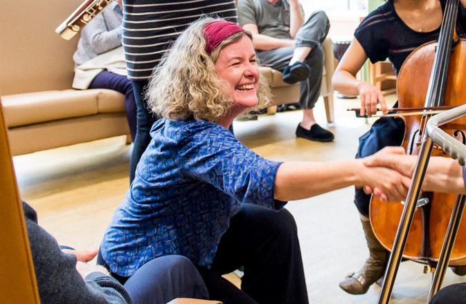 Jane bentley reached and shakes a hand with an older man. The image is cropped on Jane smiling.