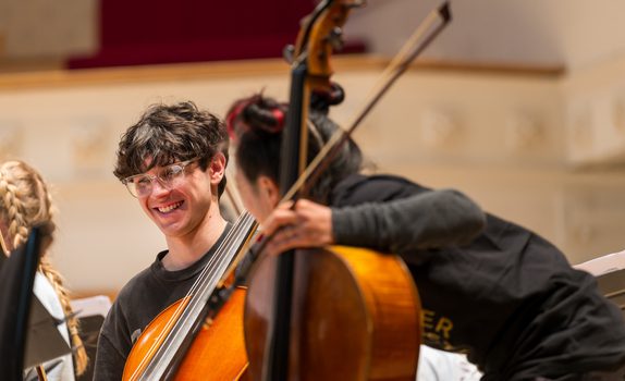 Sua and a student smile over cellos