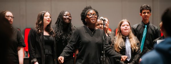 A girl stands to the mic for a solo with the Castlebrae Voices choir.