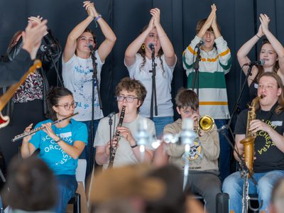 Participants perform including singers, a flautist, clarinetist, trumpeter and trombone.