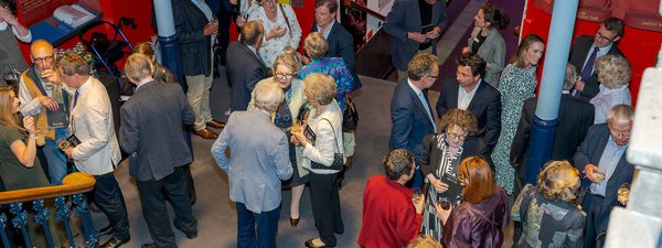 A group of people talk in a foyer - all dressed smartly