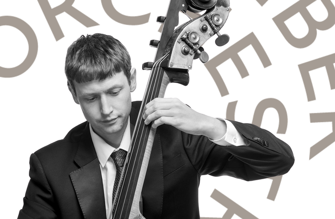Jamie plays the double bass. He wears a black suit.