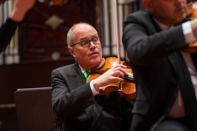 Brian Schiele plays viola. He wears a black suit and green tie.