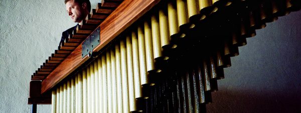 A marimba seen sideways on from a low angle, with Colin Currie just visible behind it