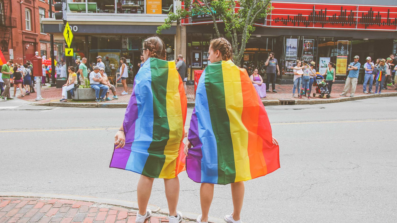 Two girls wearing rainbow cloaks
