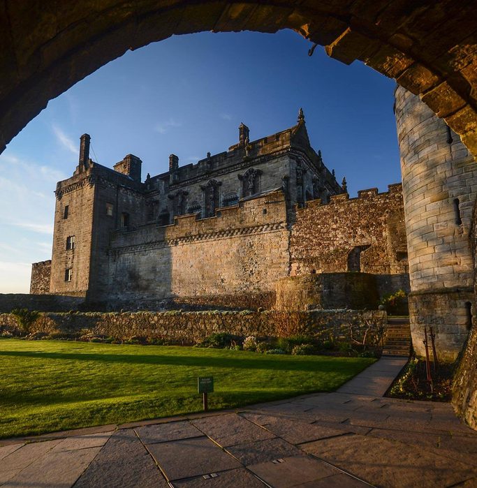 Part of Stirling Castle shot through an arch with Queen Anne's garden in the foreground.